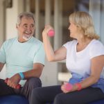 Senior couple sitting on fitness balls with dumbbells